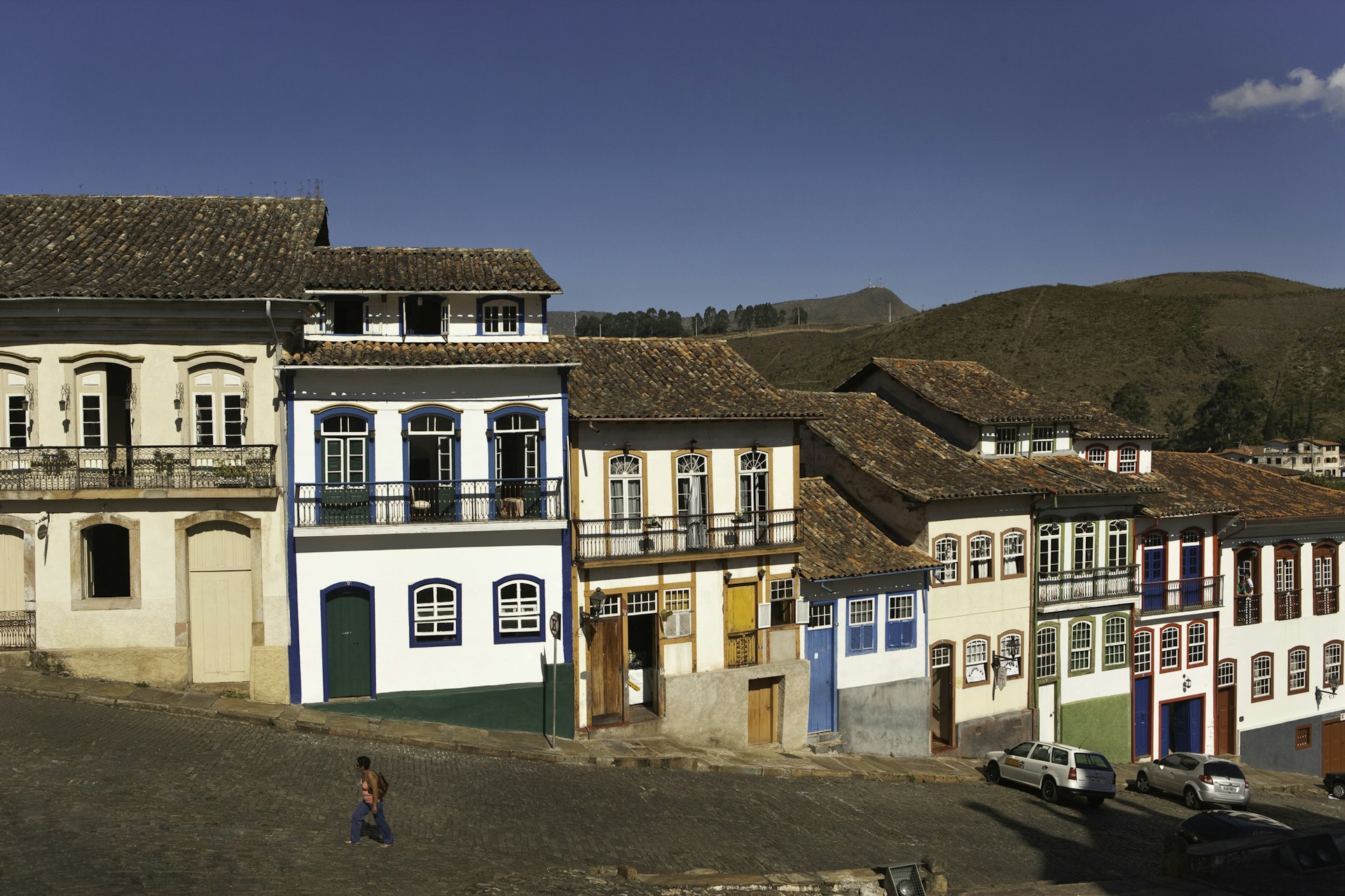 Woman walking past colorful colonial architecture in Ouro Preto, Brazil